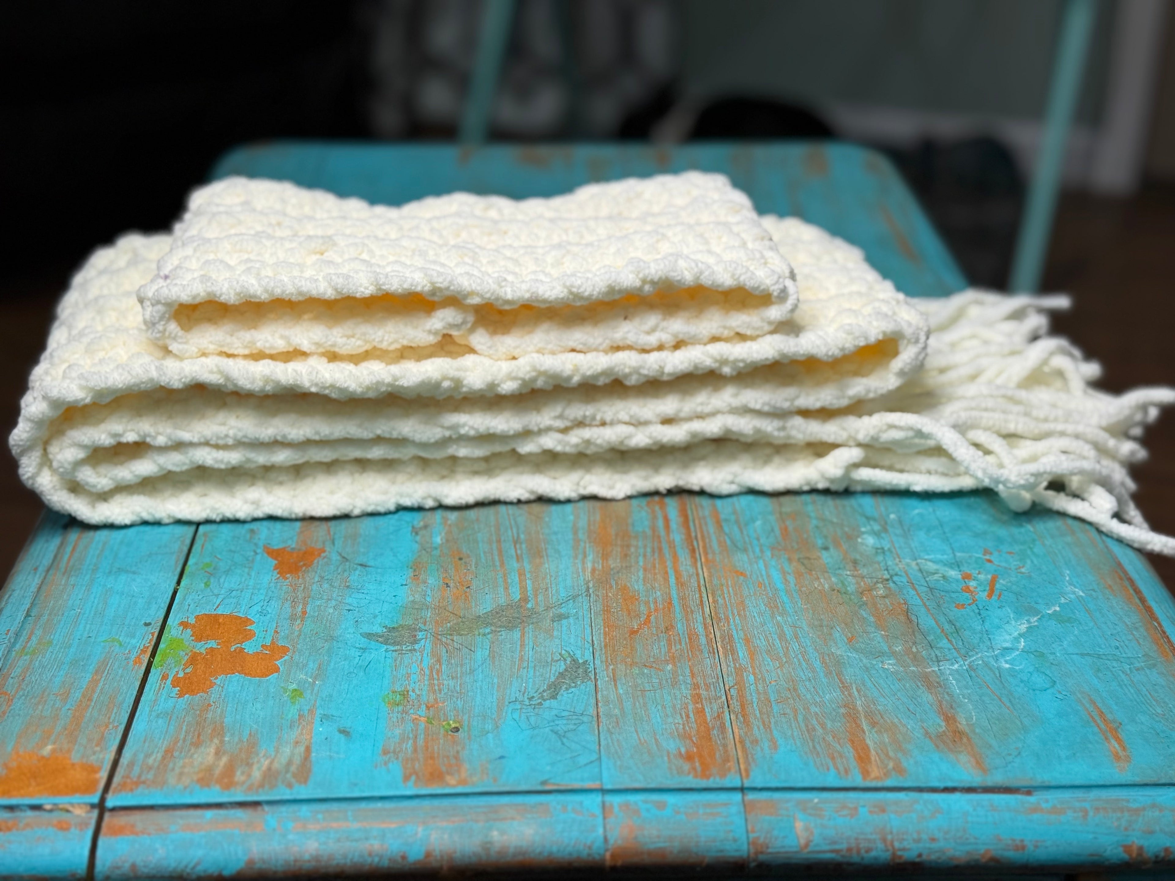 Folded Chenille Scarf on a rustic wooden turquoise table.