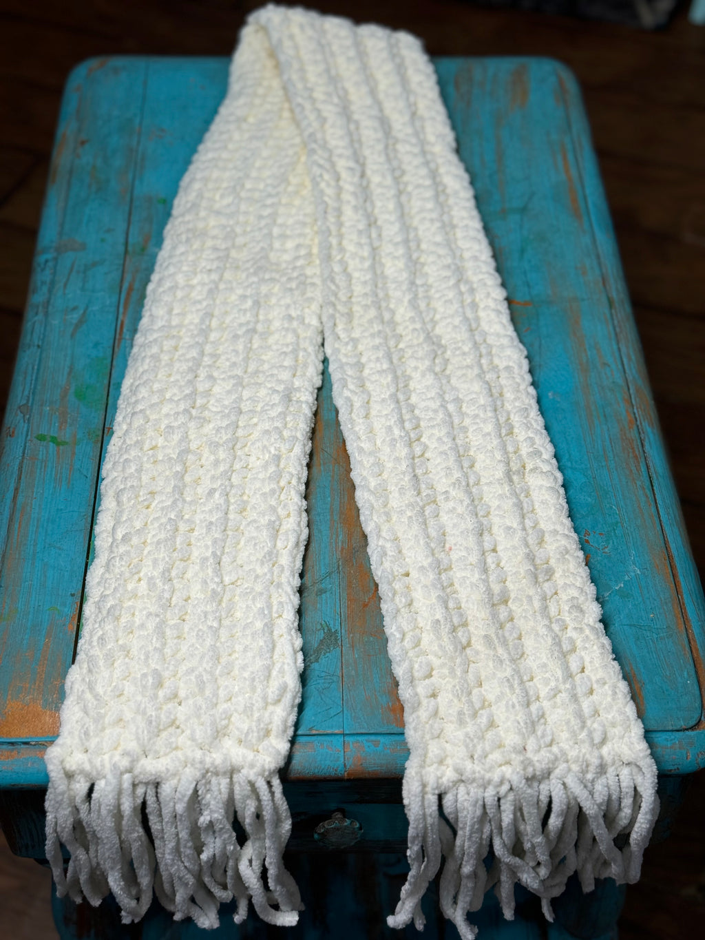 White knitted chenille scarf with fringes on a turquoise blue wooden rustic table.